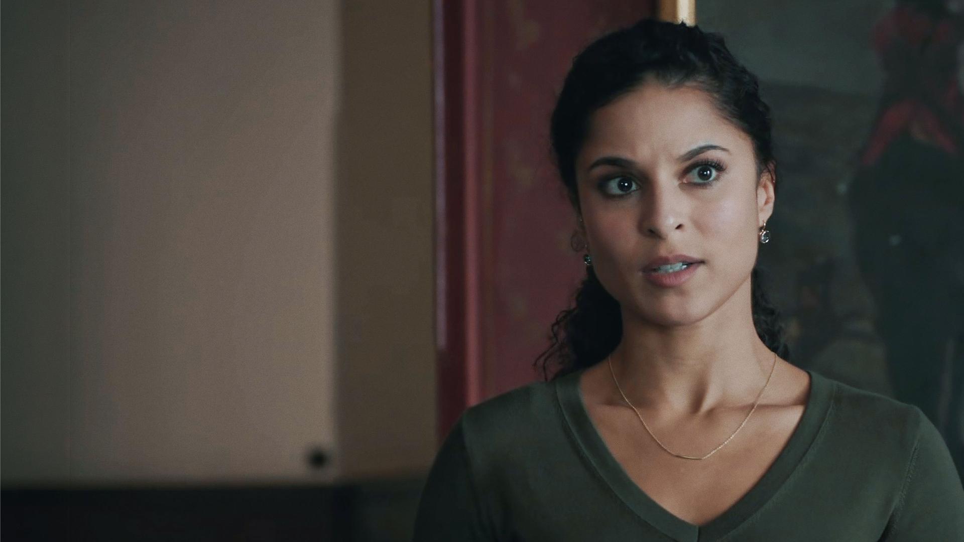 Tessa Tilker (Patricia Meeden) in einem Innenraum vor einem dunklen, kaum erkennbaren Ölgemälde. 