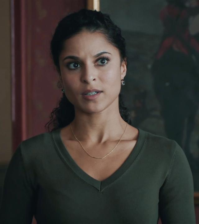Tessa Tilker (Patricia Meeden) in einem Innenraum vor einem dunklen, kaum erkennbaren Ölgemälde. 