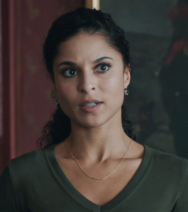 Tessa Tilker (Patricia Meeden) in einem Innenraum vor einem dunklen, kaum erkennbaren Ölgemälde. 