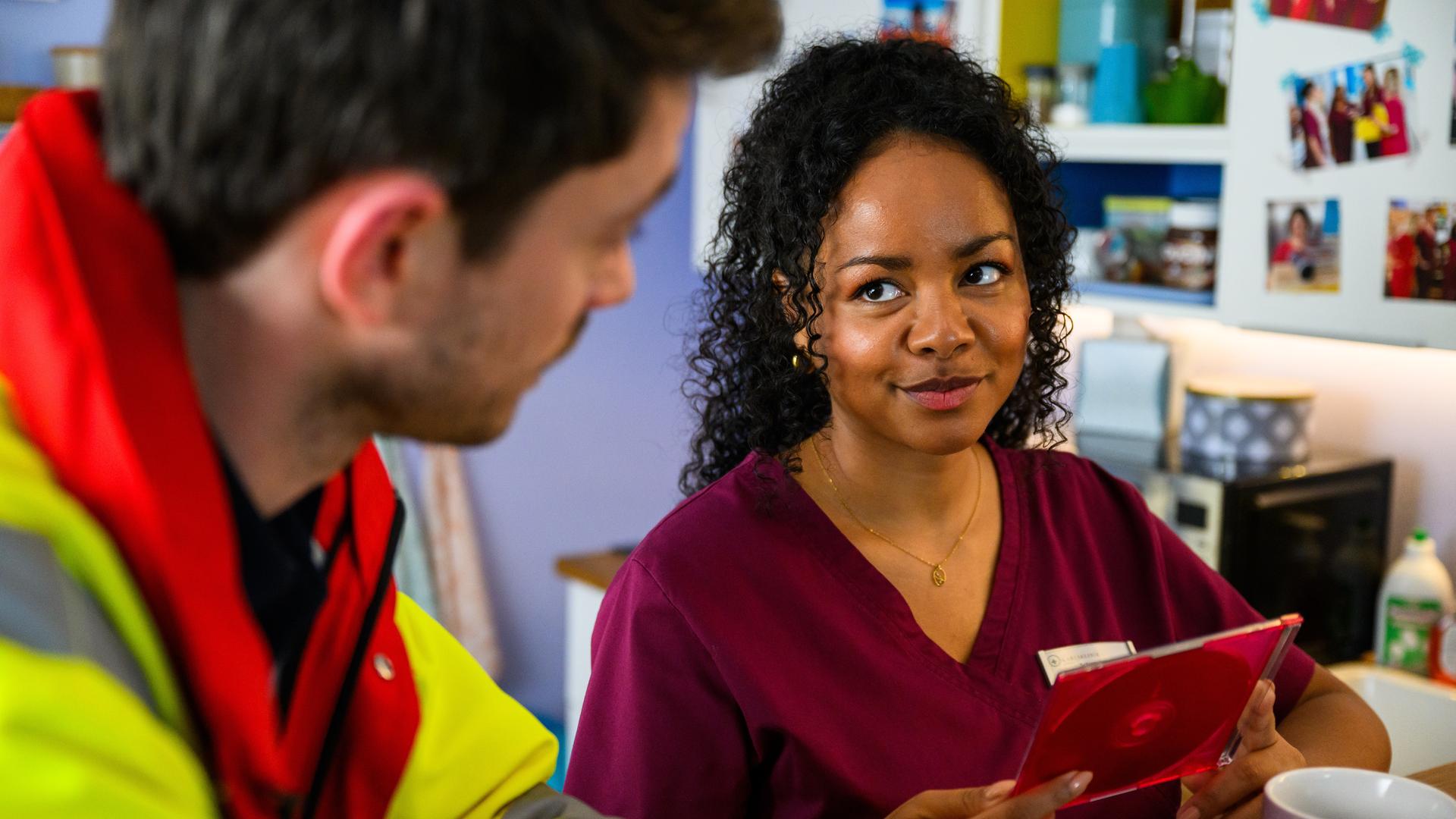 "Bettys Diagnose - Geplatzte Träume": Zoe (Catherine Chikosi) schaut Robin (Josia Krug) verliebt an und hält dabei eine DVD in beiden Händen.