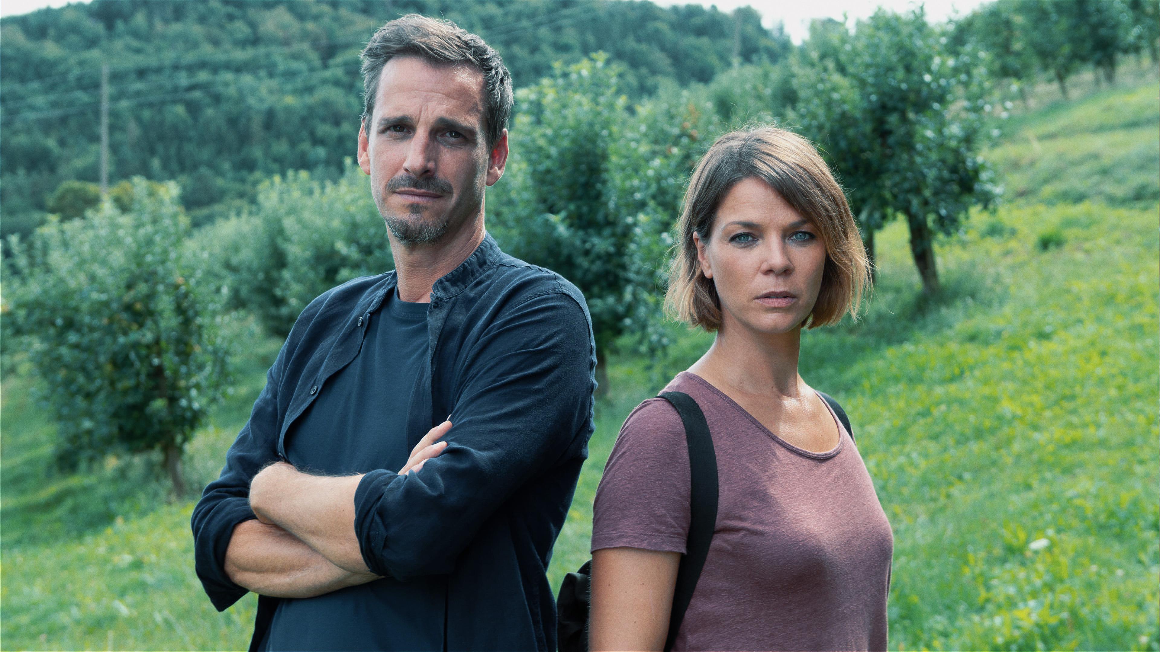 Die Kommissare Konrad Diener (Max von Thun) und Maris Bächle (Jessica Schwarz) stehen nebeneinander auf einer Wiese und schauen in die Kamera.