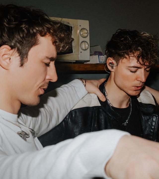 Heiko und Roman Lochmann stehen im Kreis mit einer dritten Person und haben ihre Hände auf die Schultern der anderen gelegt.