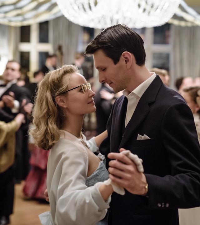 "Ku'damm 56 - Teil 3": Monika Schöllack (Sonja Gerhardt, mittig) und Freddy Donath (Trystan Pütter, rechts) tanzen auf dem Abschlussball der Tanzschule Galant Rock 'n' Roll. Um sie herum viele tanzende Menschen.
