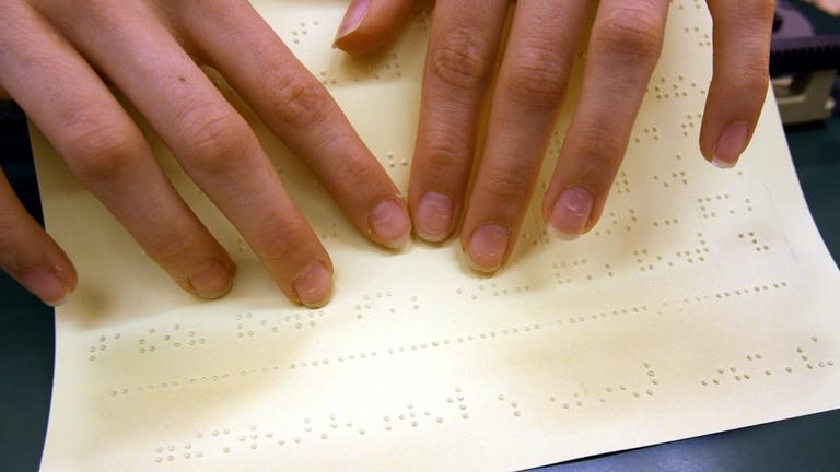 Blinde können dank der Brailleschrift mit den Fingern lesen.