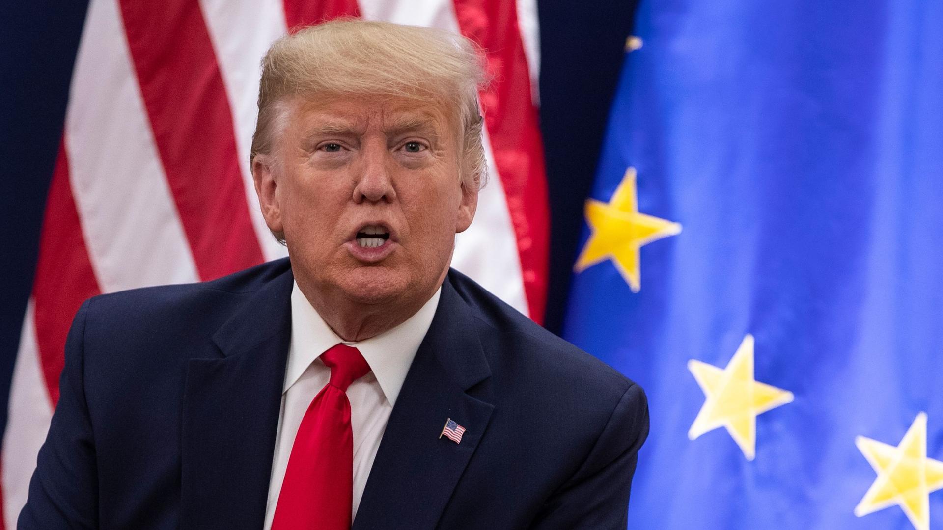 Donald Trump vor Flaggen der USA und der EU. Archivbild