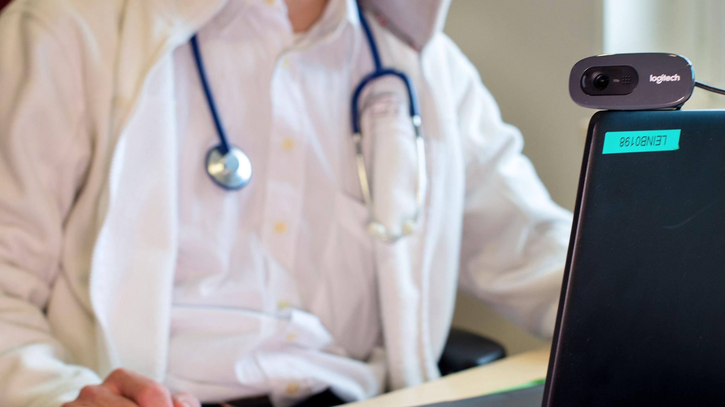 Ein Arzt sitzt vor einem Laptop. Illustration