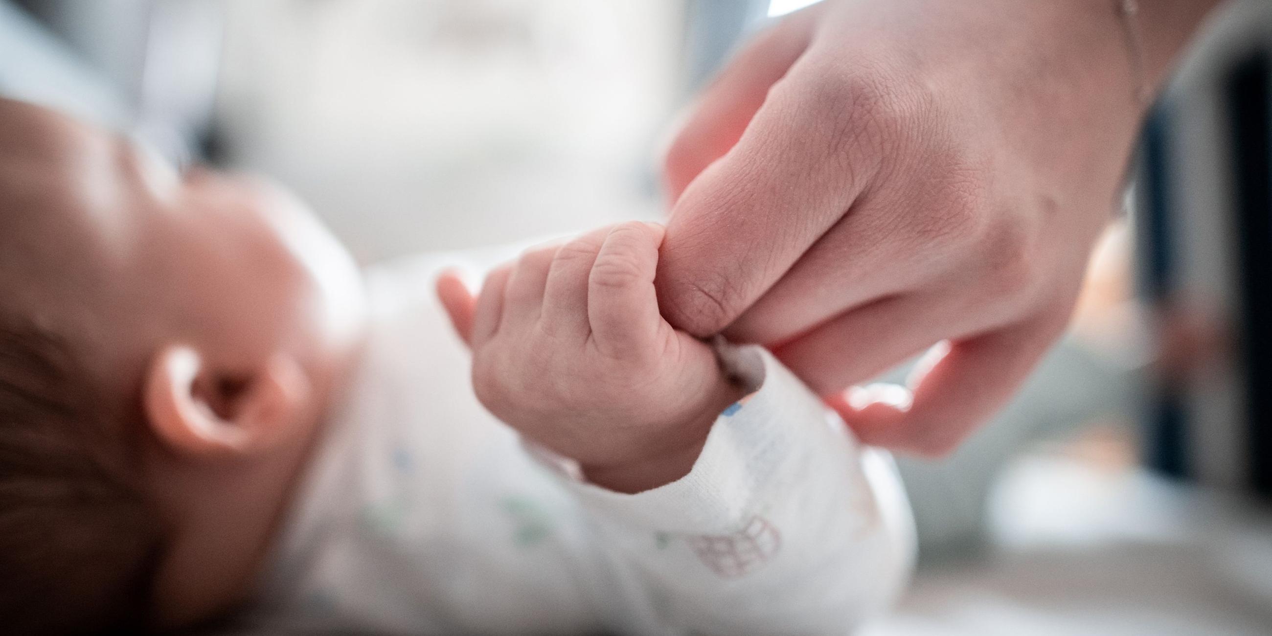 Ein Baby klammert sich an einen Finger