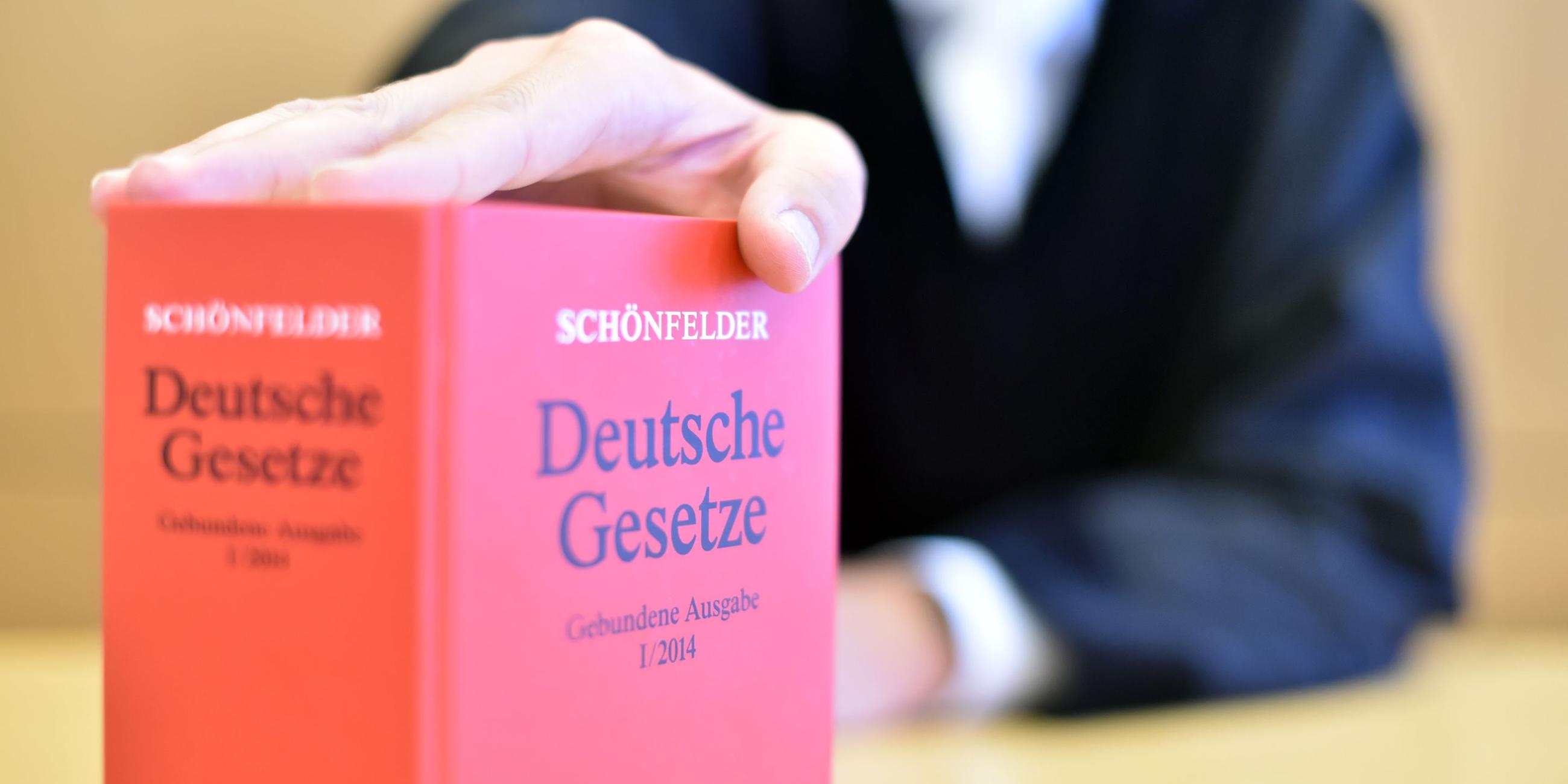 Ein Richter hinter einem Buch mit Deutschen Gesetzen. Archivbild