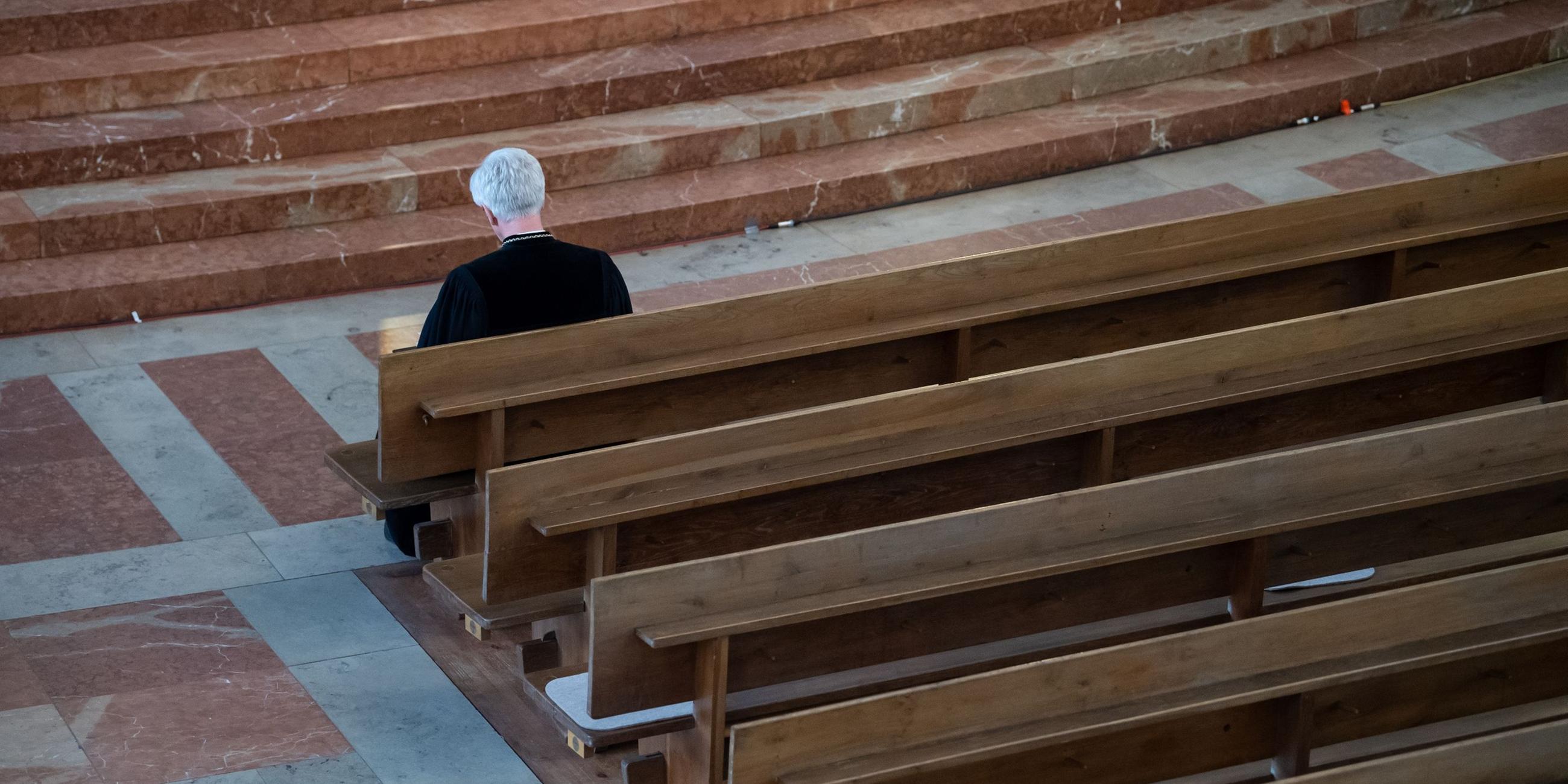 Eine Person sitzt in einer Kirchenbank. Archivbild
