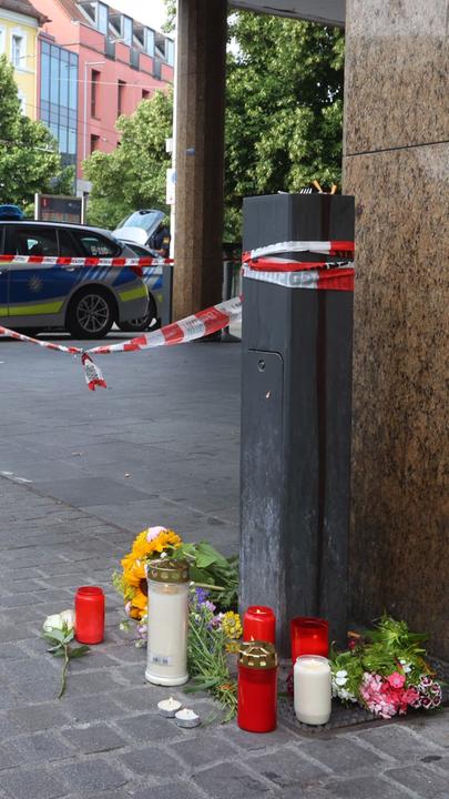 Kerzen und Blumen vor dem abgesperrten Geschäft.