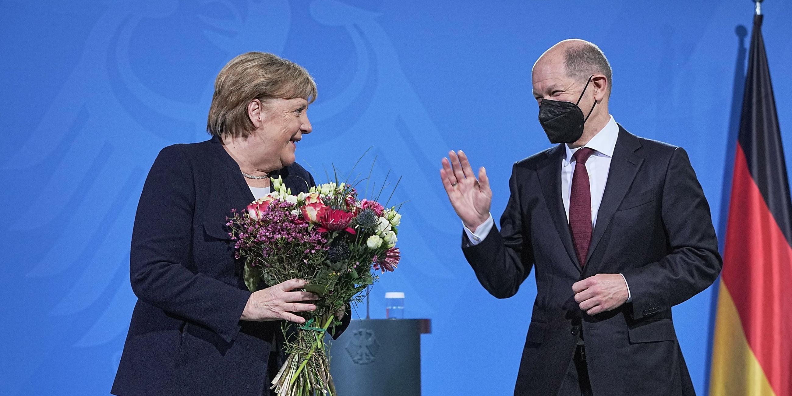 Olaf Scholz (r.) übergibt im Kanzleramt Blumen an Angela Merkel.