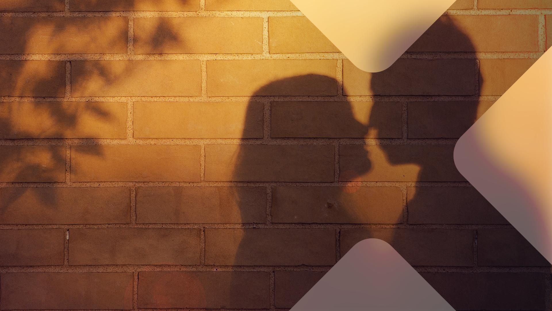 Der Schatten eines Paares wird an eine Mauer geworfen. 