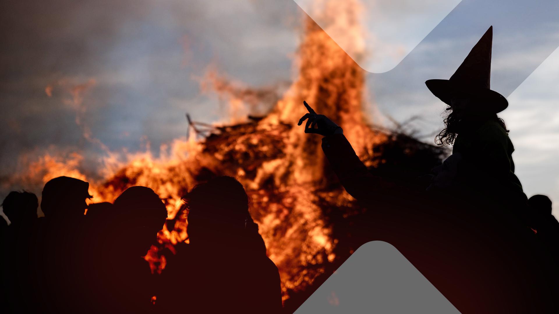 Eine als Hexe verkleidete Frau vor einem Lagerfeuer. 