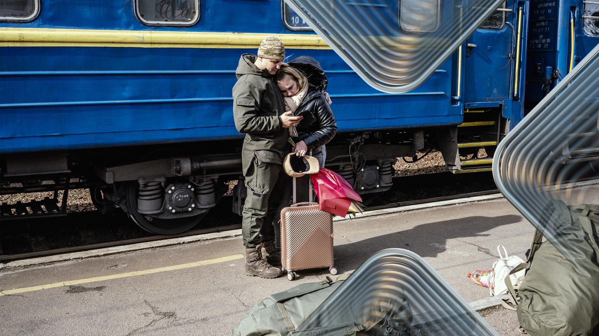 Ukrainischer Soldat mit Partnerin in Umarmung, im Hintergrund ein Zug in ukrainischen Farben blau-gelb