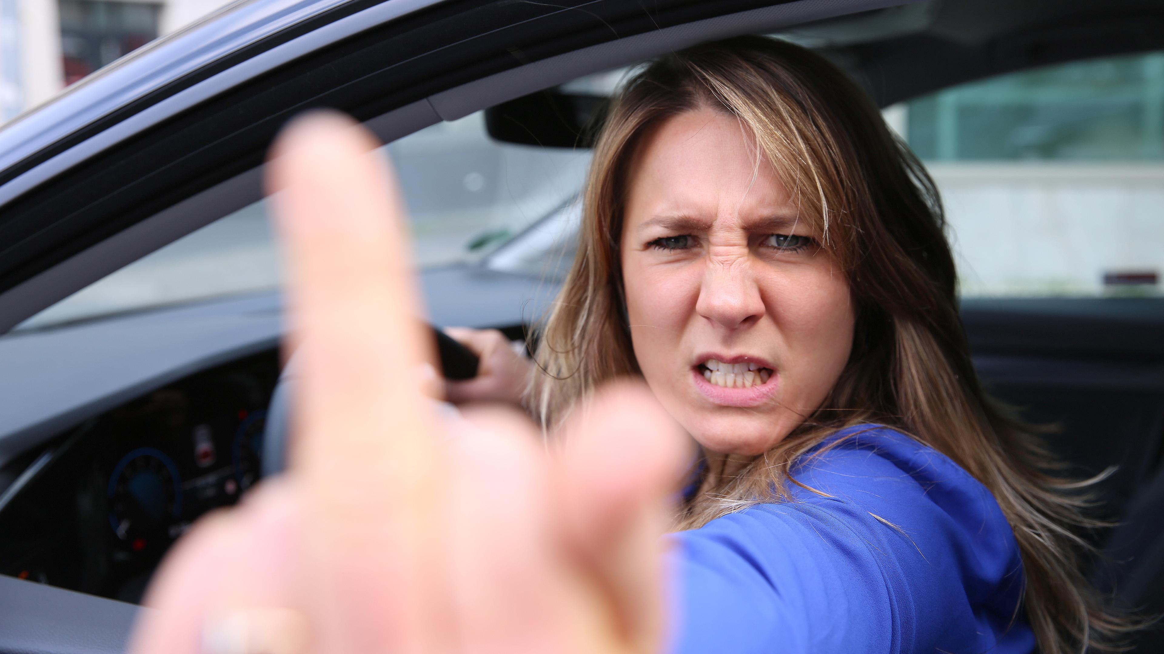 Jasmina Neudecker schaut wütend aus dem Auto-Fenster und zeigt ihren Mittelfinger in die Kamera.