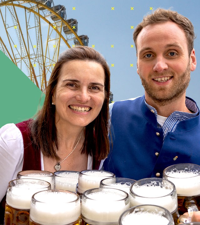 Leon Windscheid neben einer Frau im Dirndl, die mehrere Krüge Bier hält. Im Hintergrund ein Riesenrad.