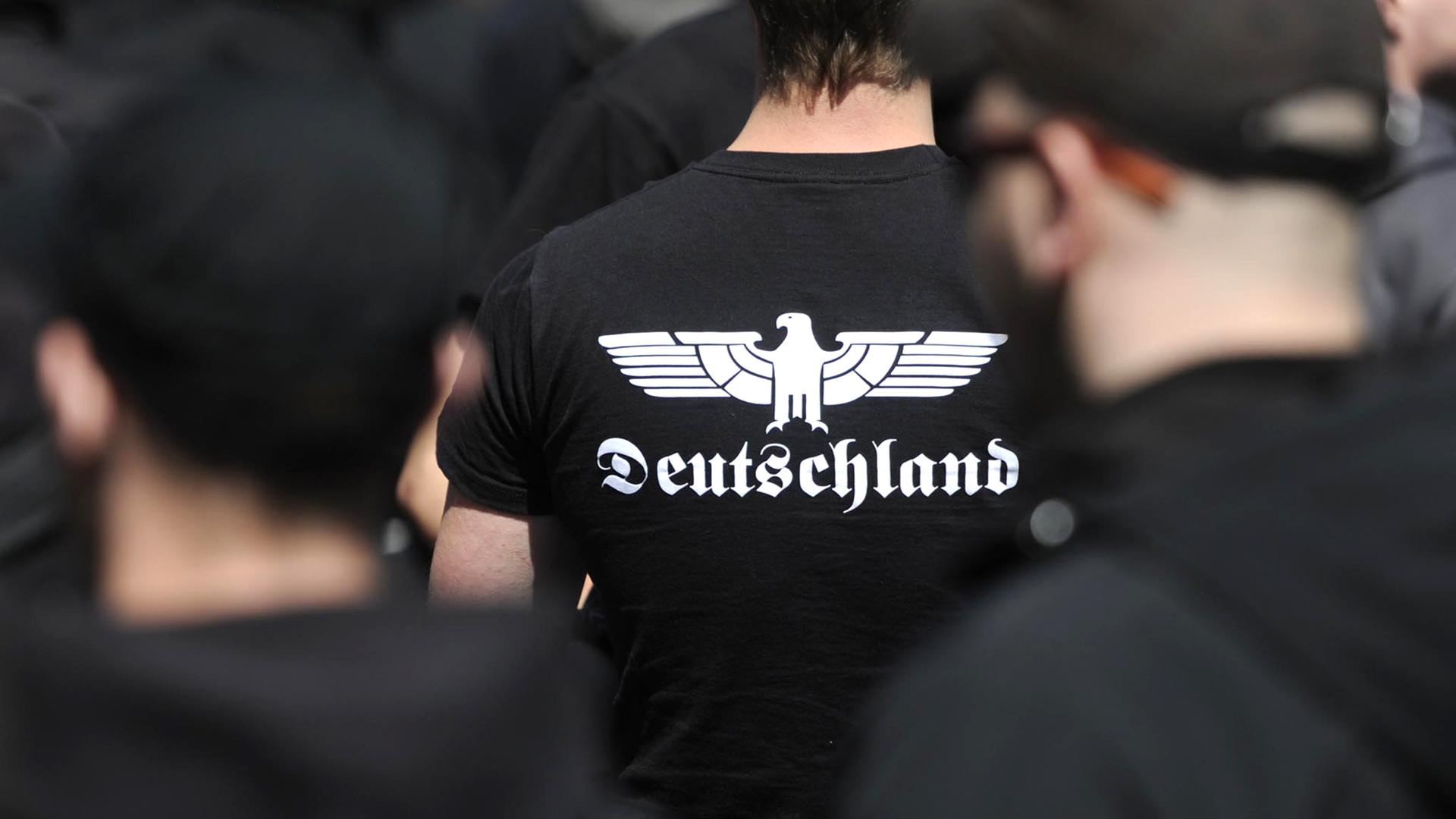 Auf einer rechtsextremen Demonstration trägt ein Neonazi ein T-Shirt mit stilisiertem Adlermotiv und der Aufschrift Deutschland.