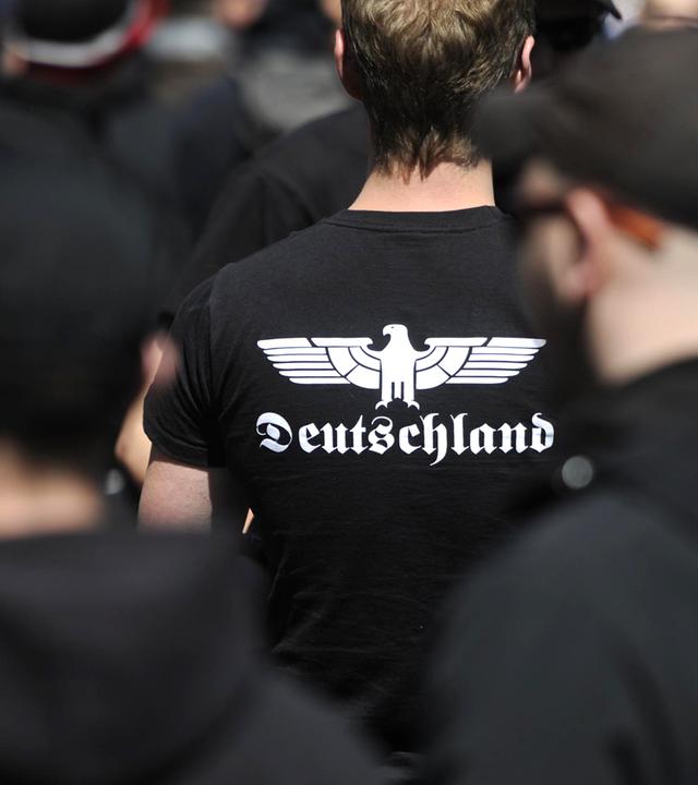 Auf einer rechtsextremen Demonstration trägt ein Neonazi ein T-Shirt mit stilisiertem Adlermotiv und der Aufschrift Deutschland.