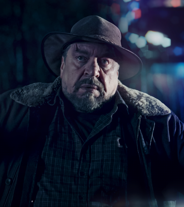 Wilhelm Grebe (Armin Rhode) steht mit erhobenen Händen an einer Straße.