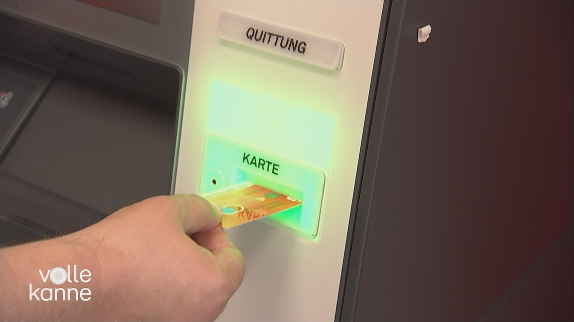 Karte wird an einen Geldautomaten gehalten.