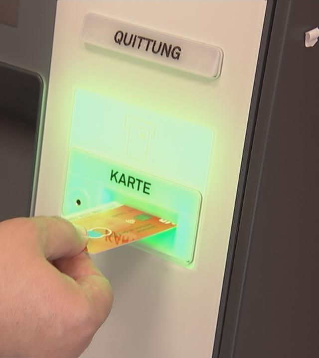 Karte wird an einen Geldautomaten gehalten.