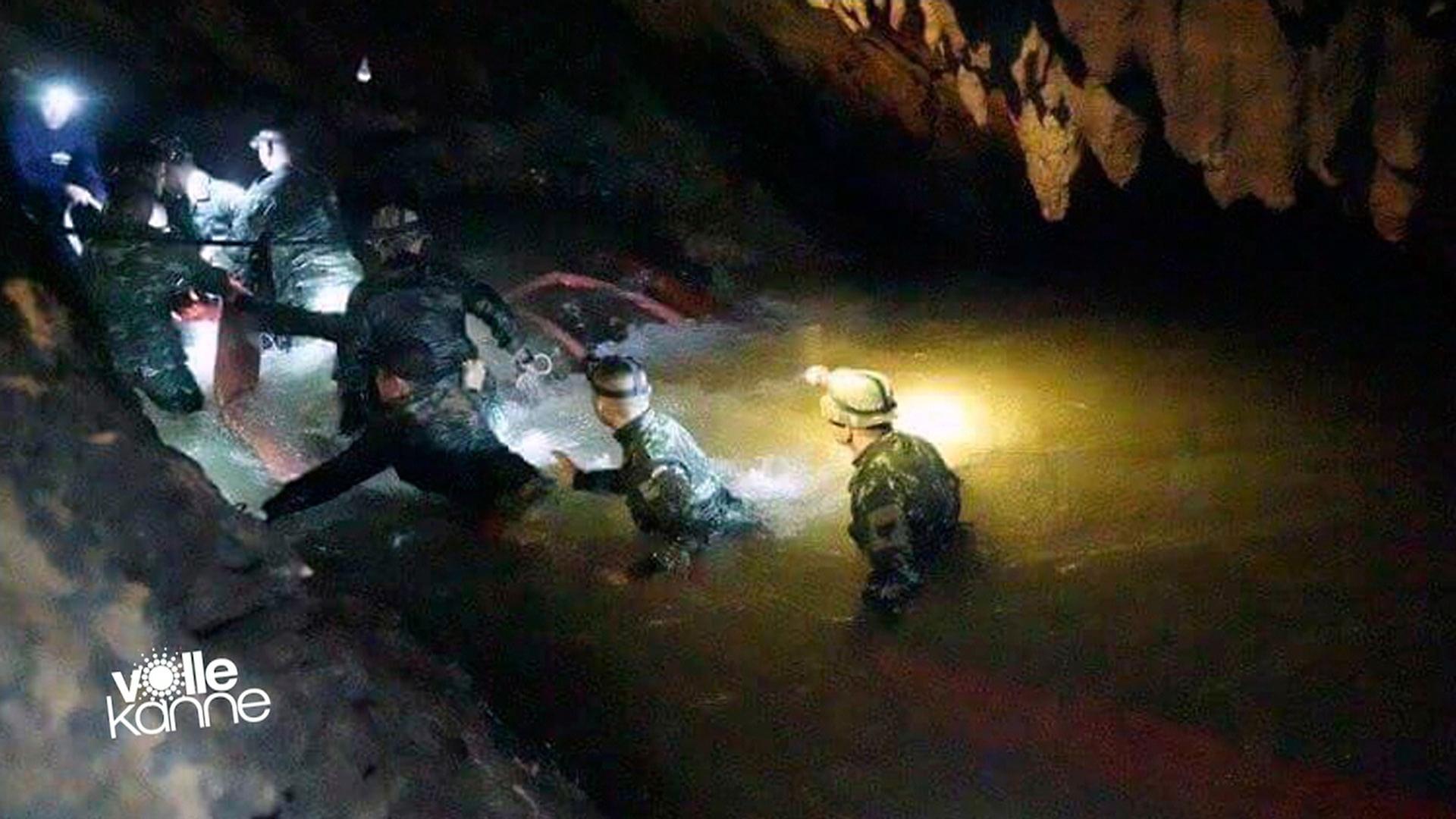 Rettungskräfte gehen durch Wasser in einer Höhle