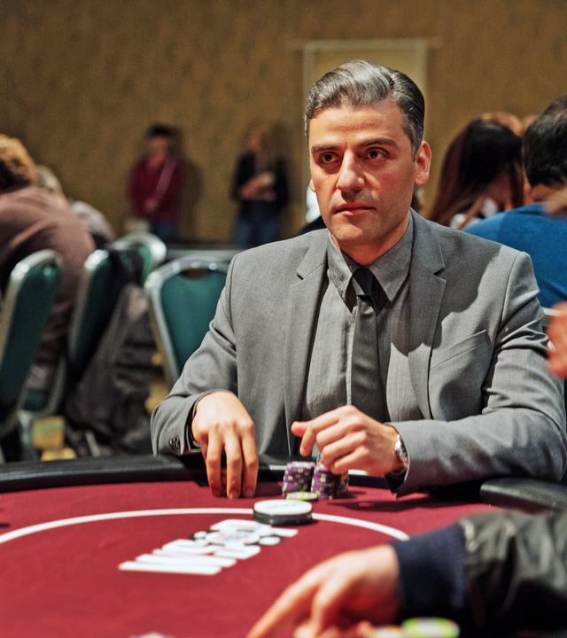William Tell (Oscar Isaac) sitzt in einem grauen Anzug und Krawatte an einem Pokertisch. Vor ihm liegen zwei Stapel Chips und er schaut konzentriert nach vorn. Um ihn herum sind verschwommen weitere Spieler zu sehen.