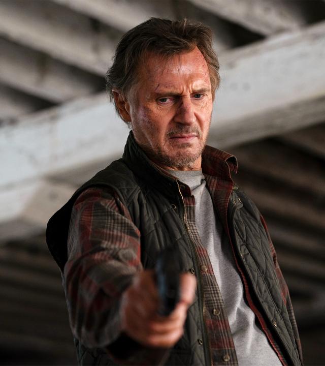Jim Hanson (Liam Neeson) steht unter einer Brücke, hält eine Waffe in ausgestreckter Hand und blickt ernst nach unten.