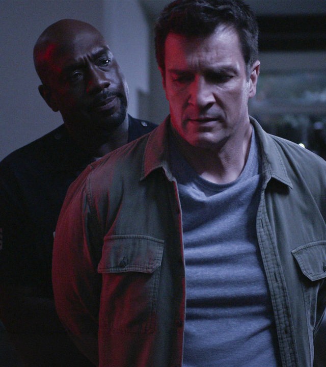 "The Rookie - Abwärts": Nolan (Nathan Fillion) steht mit den Armen hinter seinem Rücken vor Sergeant Grey (Richard T. Jones), der Nolan Handschellen umlegt und ihn dabei ernst anschaut.