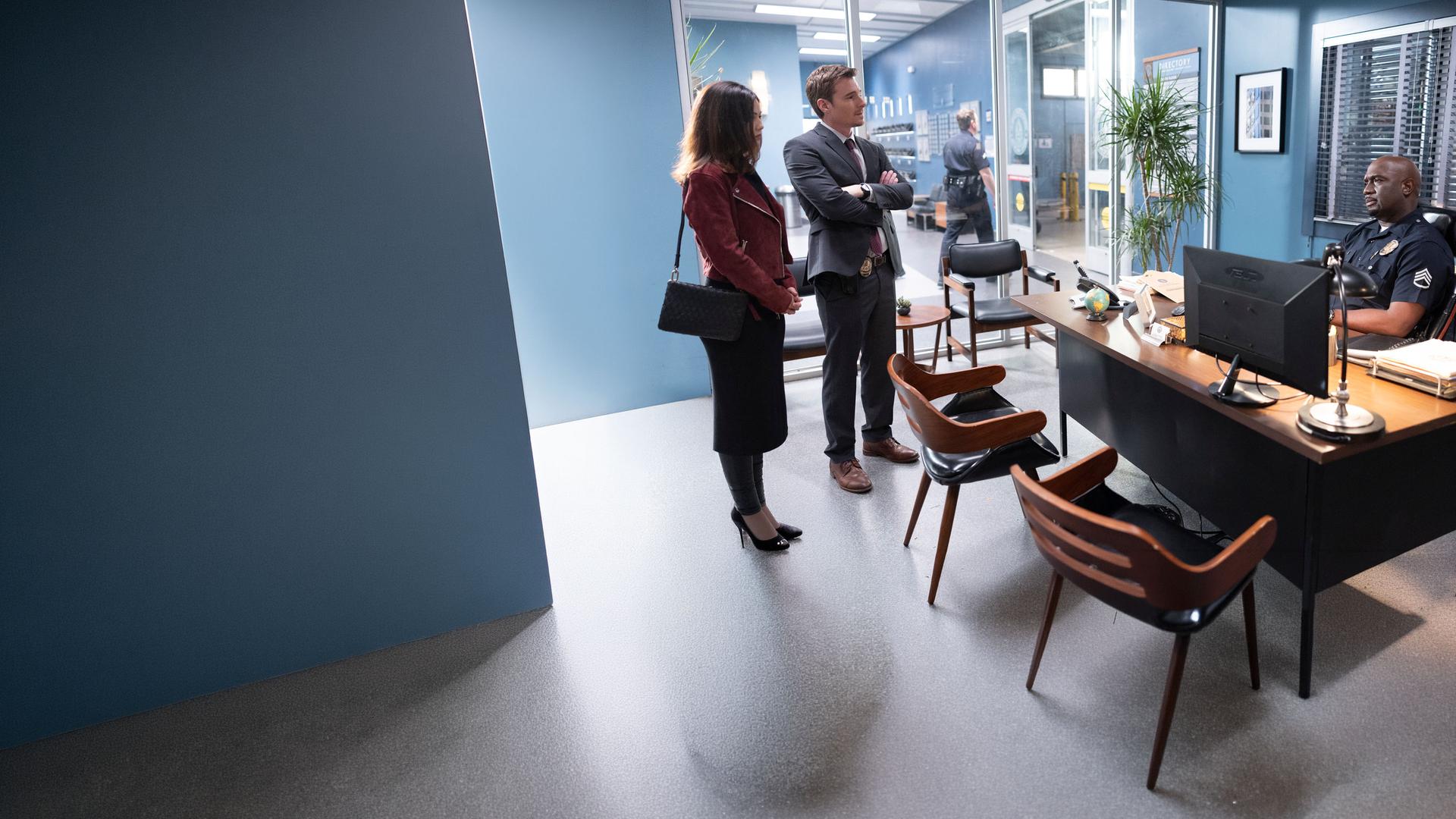 "The Rookie - Druck": Dr. London (Danielle Campbell) und Detective Pearson (Daniel Bonjour) stehen in einem Büro vor Sergeant Grey (Richard T. Jones), der an seinem Schreibtisch sitzt und sie mit skeptischem Blick mustert.