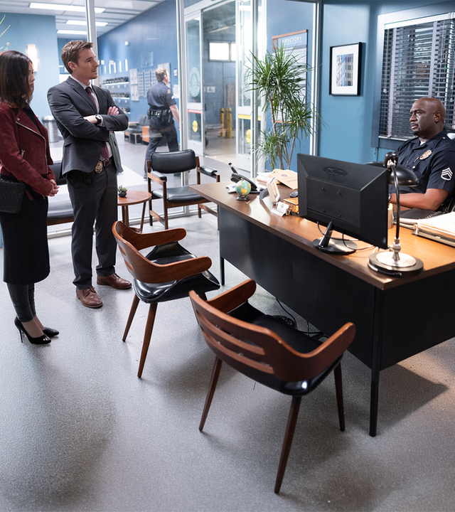 "The Rookie - Druck": Dr. London (Danielle Campbell) und Detective Pearson (Daniel Bonjour) stehen in einem Büro vor Sergeant Grey (Richard T. Jones), der an seinem Schreibtisch sitzt und sie mit skeptischem Blick mustert.