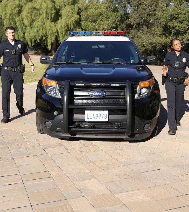 "The Rookie - Ein gefallener Stern": Nolan (Nathan Fillion) und Harper (Mekia Cox) laufen neben einem Streifenwagen her, der in einer Einfahrt geparkt ist.