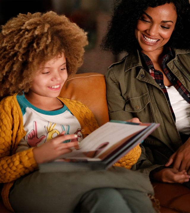 "The Rookie - Nachts": Nyla Harper (Mekia Cox) sitzt mit ihrer Tochter Lila (Carsyn Rose) auf der Couch und liest in einem Buch.