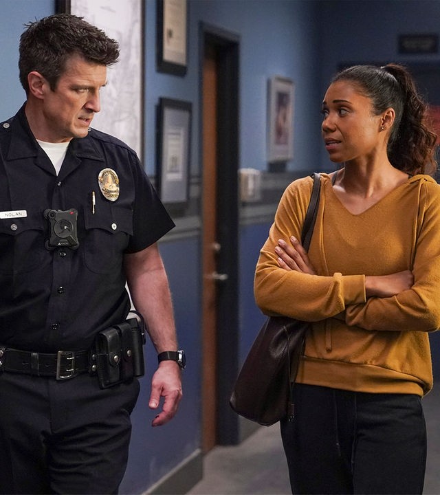 "The Rookie - Überleben": Nolan (Nathan Fillion) und Professorin Ryan (Toks Olagundoye) laufen einen Gang entlang. Während Nolan Ryan ernst anschaut, sieht Ryan verunsichert zu ihm rüber.
