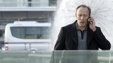 "The Team (1)": Harald Bjørn (Lars Mikkelsen) läuft eilig, telefonierend und mit einer Reisetasche in der Hand durch die Stadt.