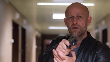  "The Team II (2)": Gregor (Jürgen Vogel) hält eine Waffe in der Hand und läuft durch den Flur des Krankenhauses.