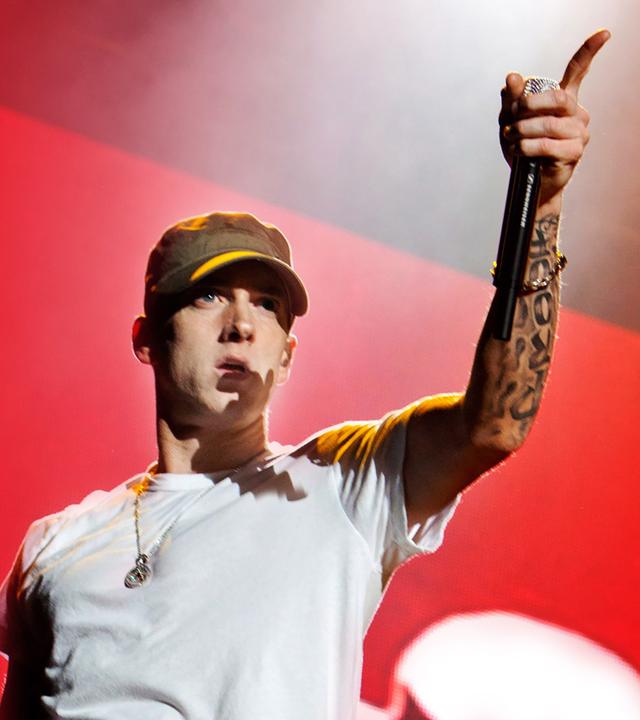 Eminem in einem weissen T-shirt vor einem roten Hintergrund