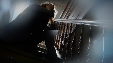 Frau sitzt im Halbdunkel auf der Treppe 