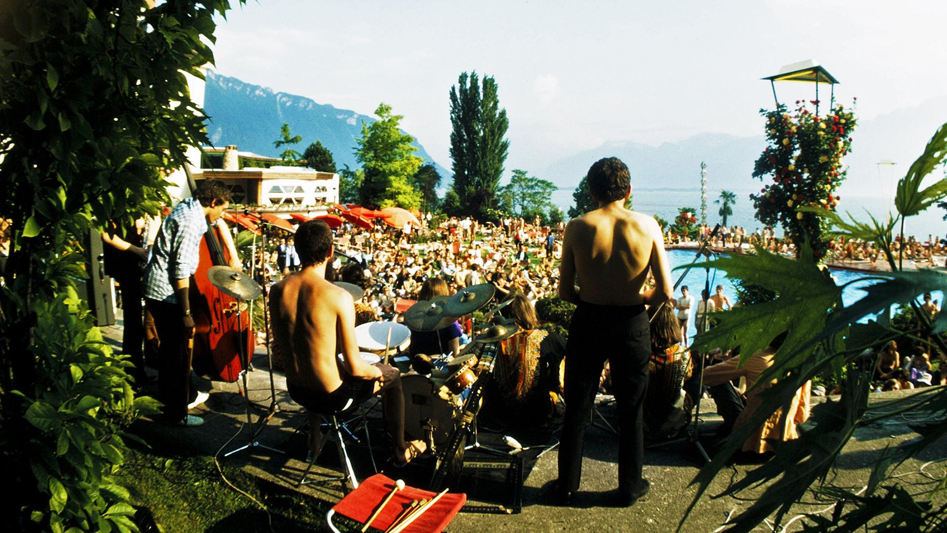 Eine Konzertbühne vor einem See mit Publikum im Hintergrund
