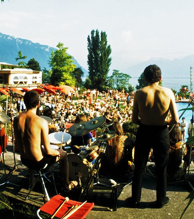 Eine Konzertbühne vor einem See mit Publikum im Hintergrund