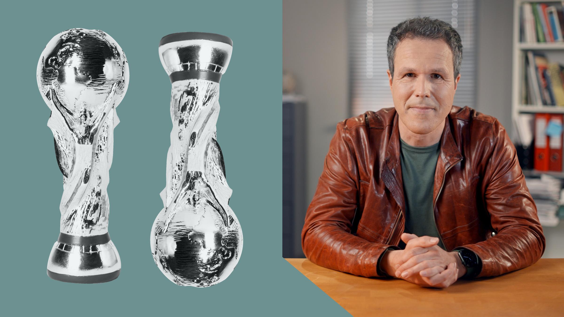 ZDF-Korrespondent Thomas Reichart, im Hintergrund die Deutschlandfahne und daneben zwei WM-Pokale, einer in silber und einer in gold