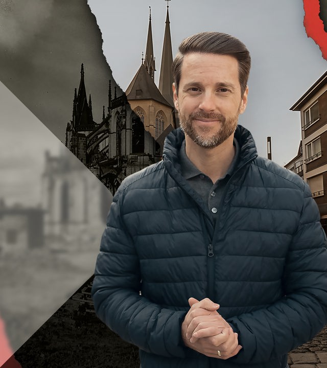 Mirko Drotschmann vor einem Dom in einer Innenstadt. 