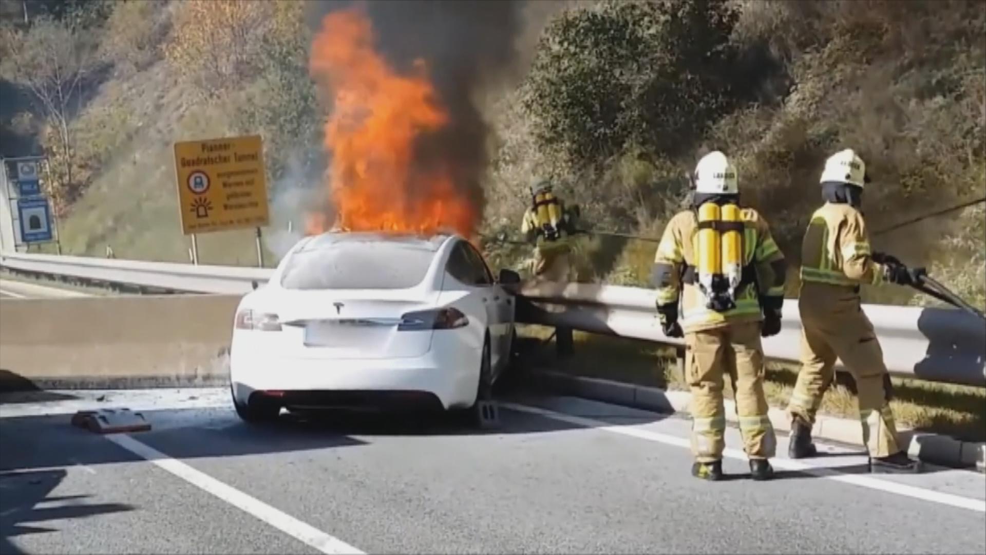 Brennendes Elektro Auto auf der Straße und Feuerwehr bei Löscharbeiten