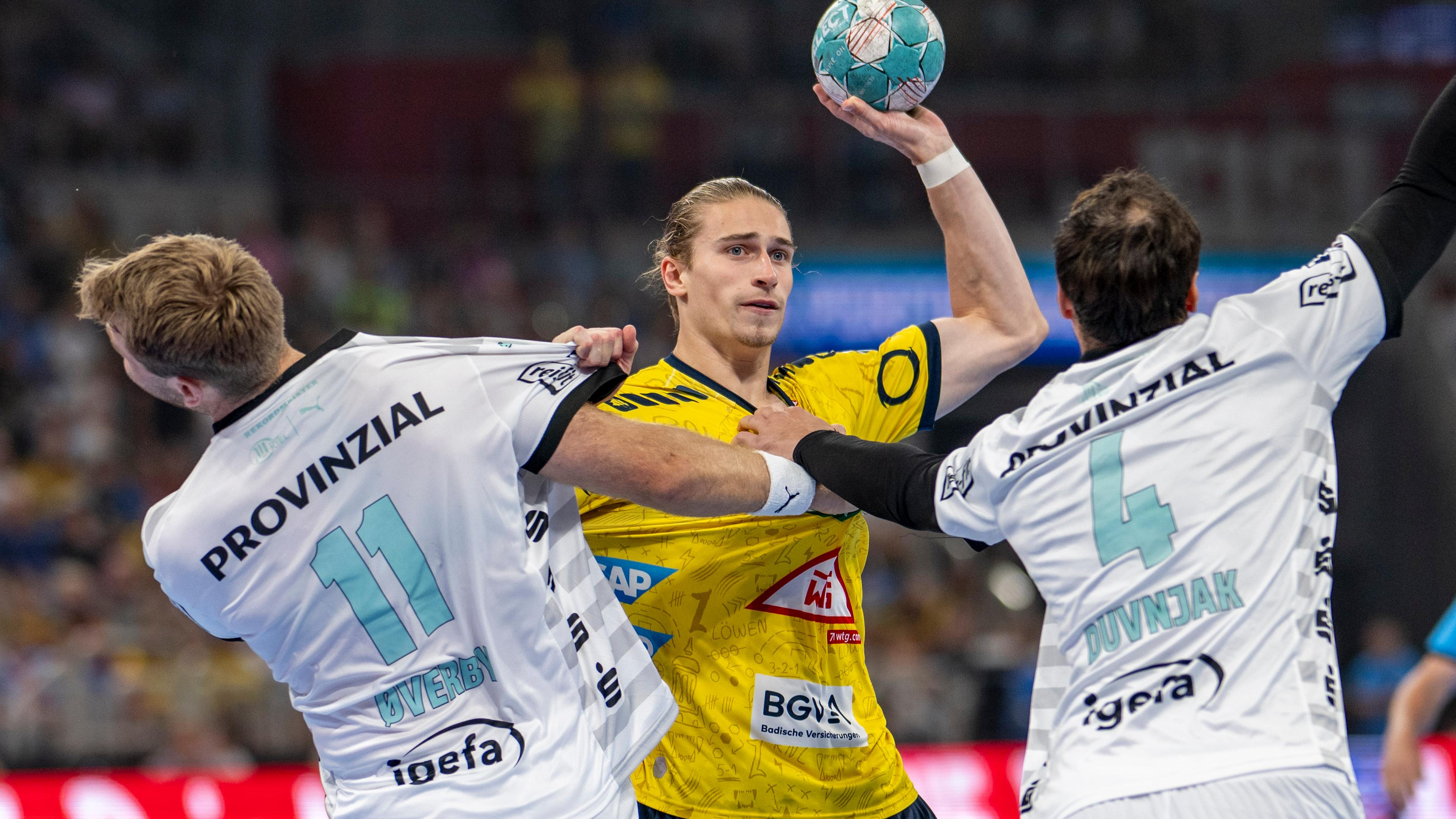Kiels Petter Overby (l-r), Juri Knorr von den Rhein-Neckar Löwen und Kiels Domagoj Duvnjak kämpfen um den Ball.