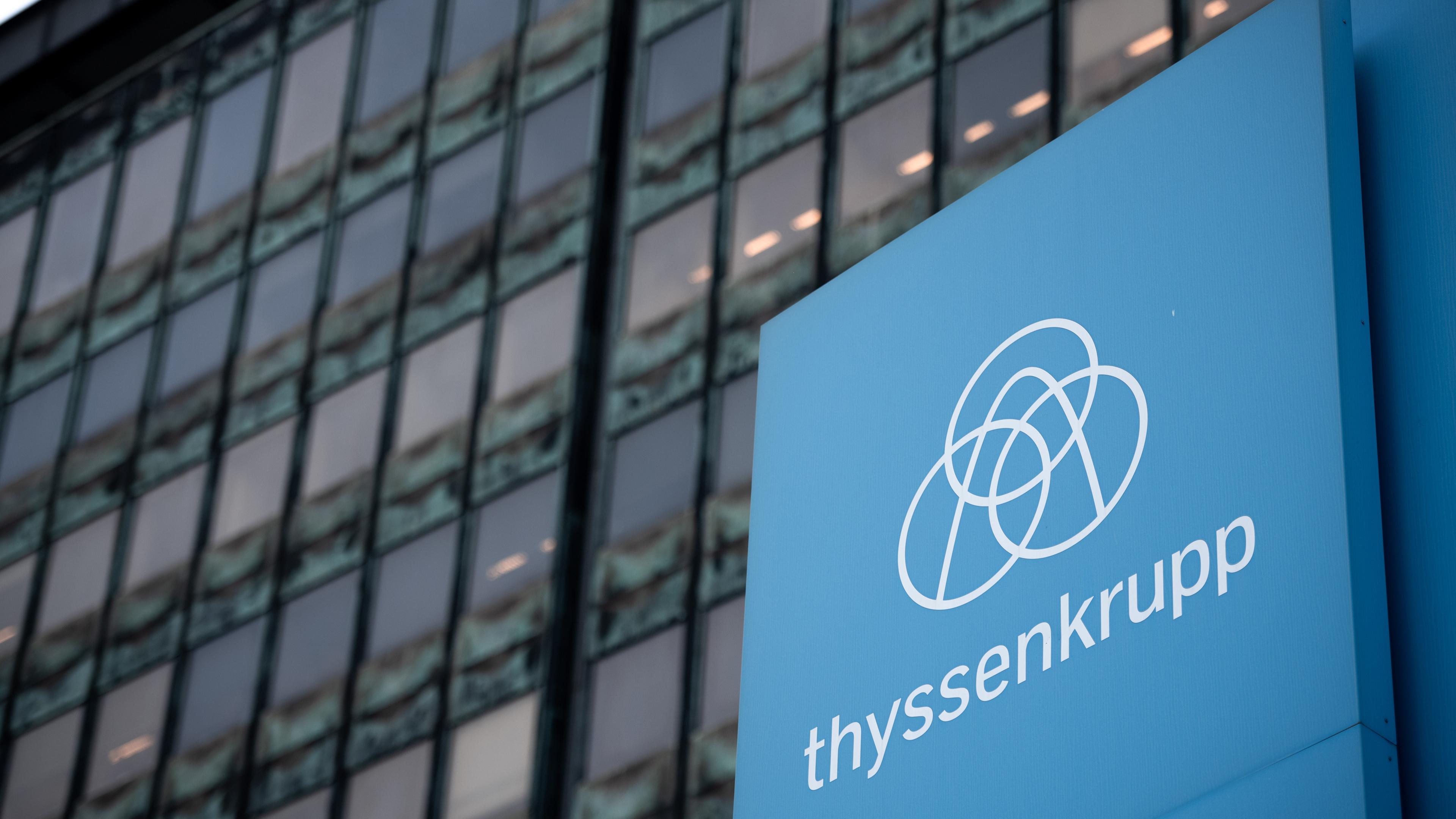 Das Logo von Thyssenkrupp auf einem blauen Schild vor dem Betriebsgebäude in Duisburg.