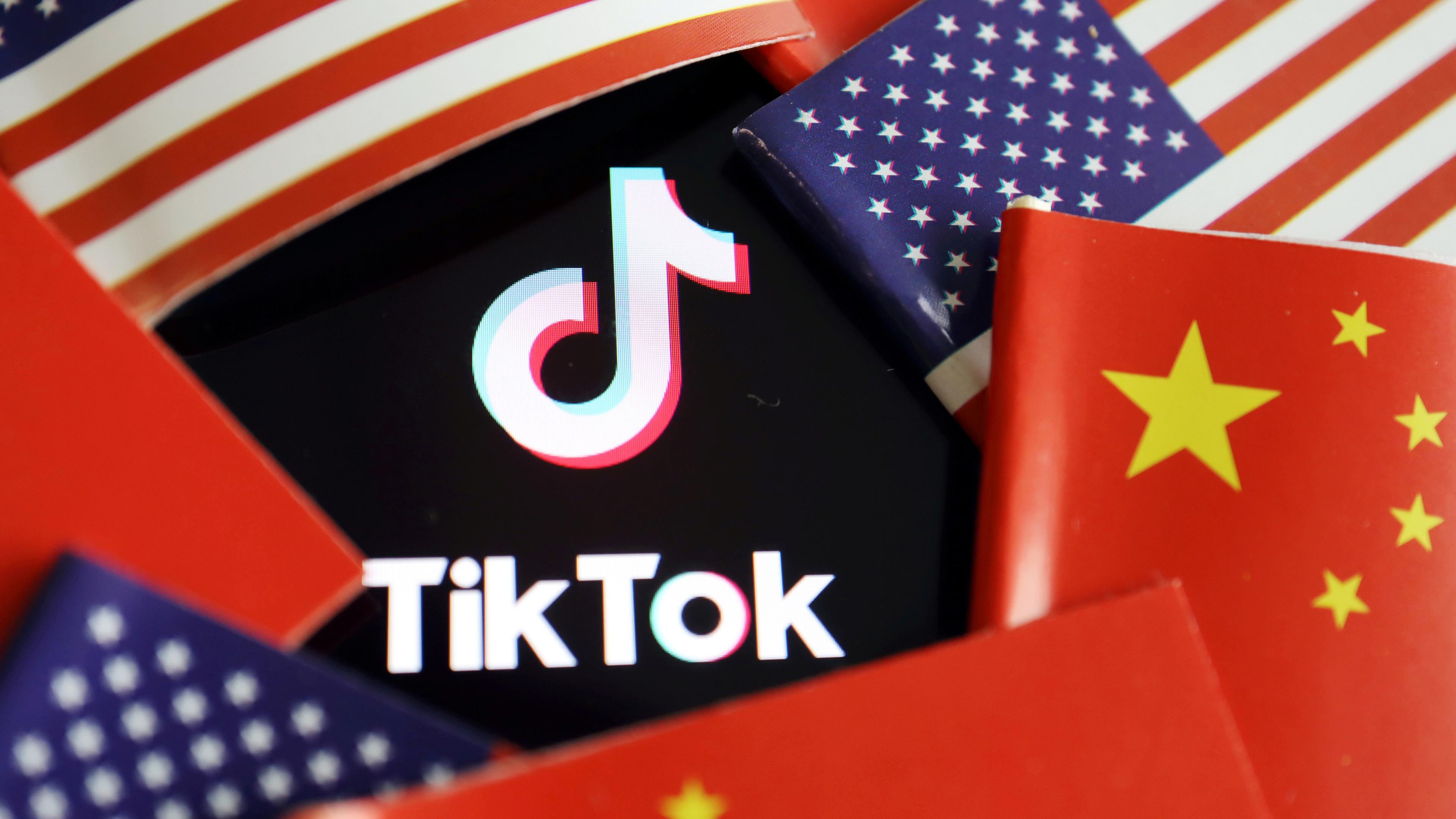 Das Logo der App TikTok, umringt von US- und chinesischen Flaggen. 