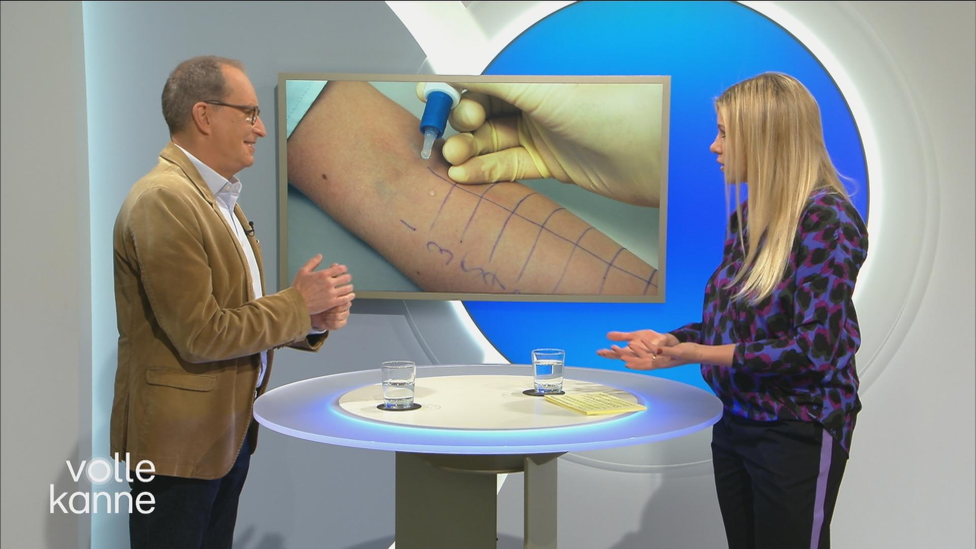 Dr. Christoph Specht im Gespräch mit Nadine Krüger. Im Hintergrund wird ein Bild eines Allergietests angezeigt.