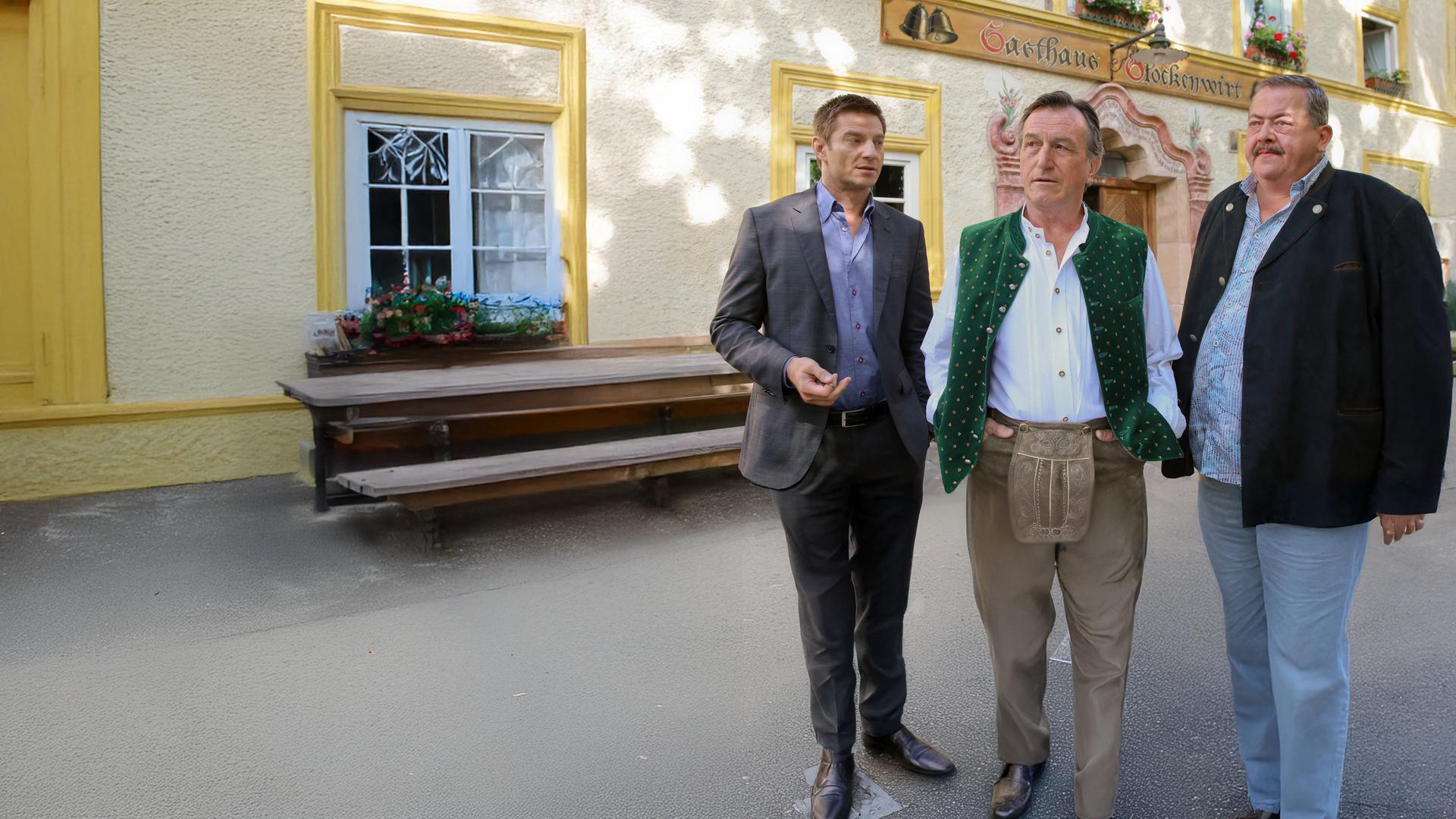 "Die Rosenheim-Cops - Tod einer Heuschrecke": Der Wirt Ludwig Bernreiter (Johann Schuler) steht zusammen mit den Kommissaren Hansen (Igor Jeftic) und Hofer (Joseph Hannesschläger) vor dem Gasthof "Glockenwirt".