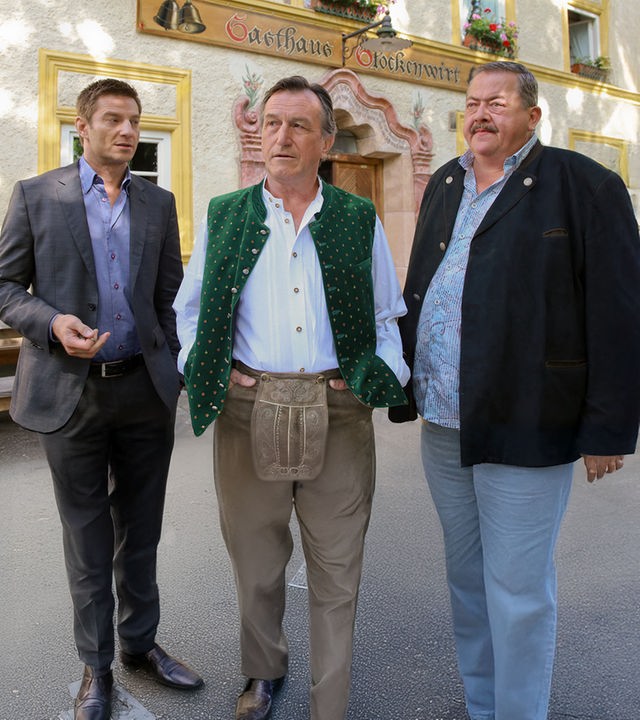 "Die Rosenheim-Cops - Tod einer Heuschrecke": Der Wirt Ludwig Bernreiter (Johann Schuler) steht zusammen mit den Kommissaren Hansen (Igor Jeftic) und Hofer (Joseph Hannesschläger) vor dem Gasthof "Glockenwirt".