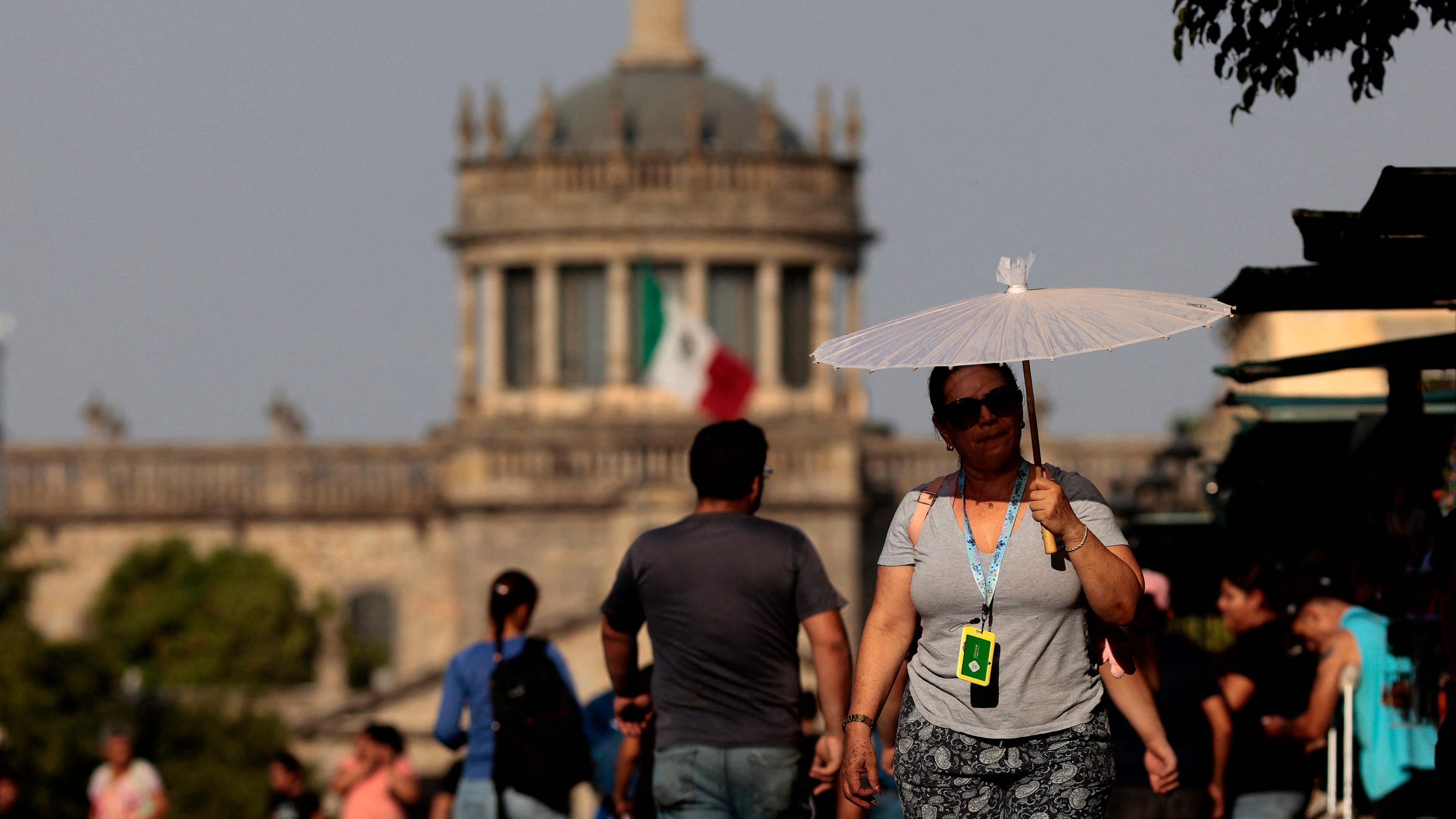 Eine Frau in Mexiko versucht sich mit einem Schirm vor der Hitze zu schützen.